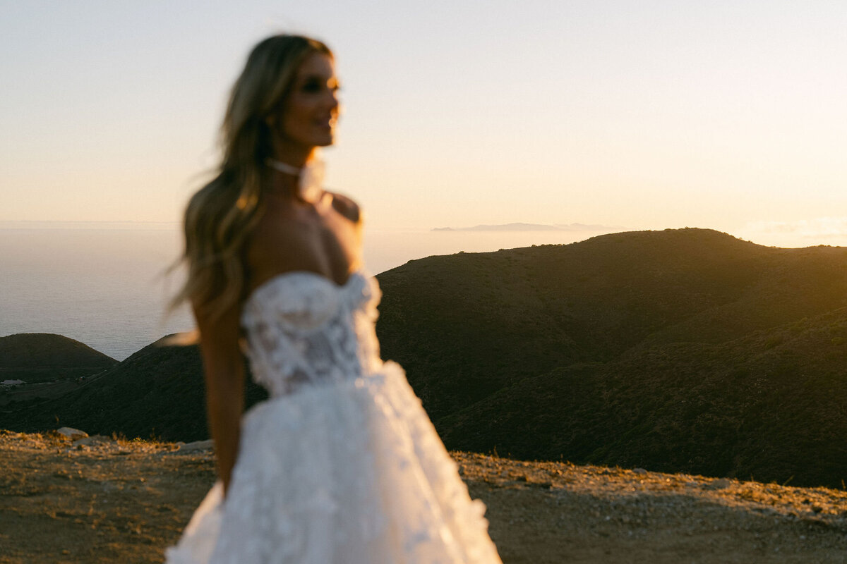 Bride in a couture gown blurry in the foreground while the camera is focusing on the islands off the Malibu coast in the background taken at Deer Creek Ridge Malibu wedding venue