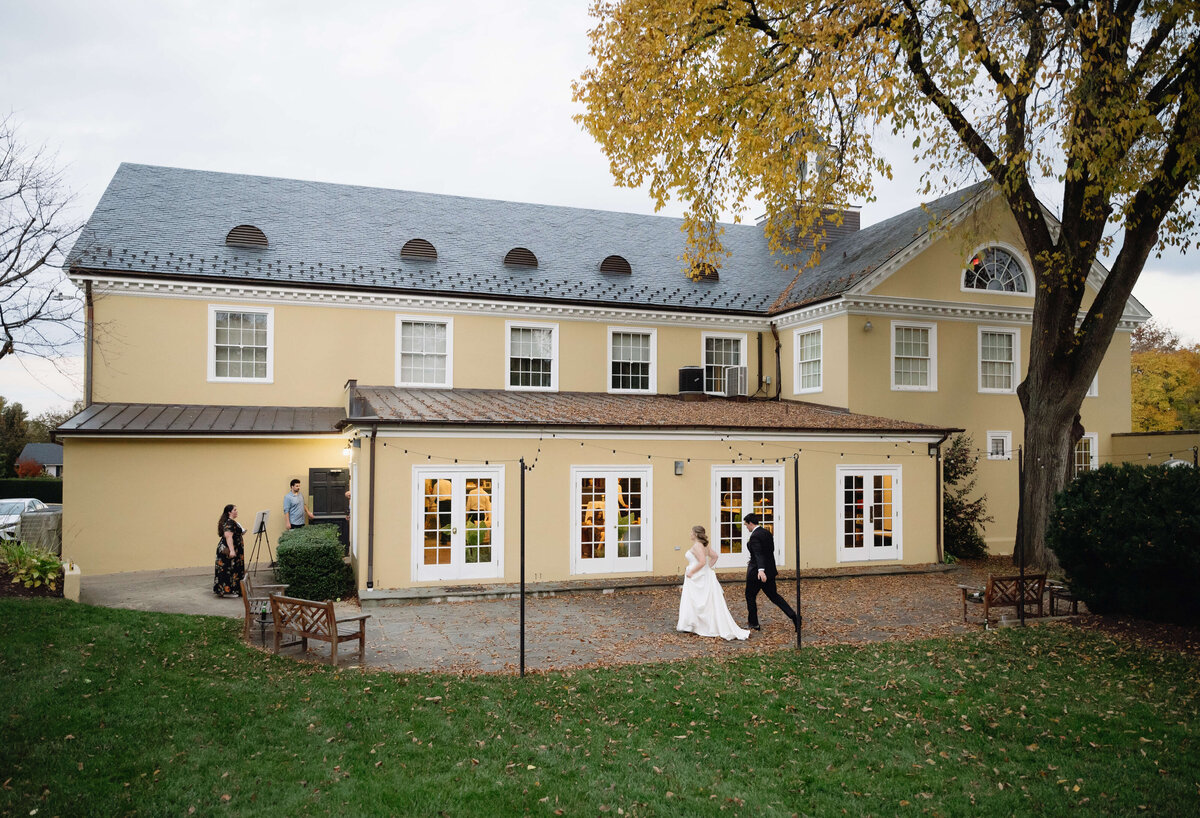 Richmond wedding venues with outdoor patios include middleburg community center which is a light yellow building with a large patio with a fresh garden and large trees on the property