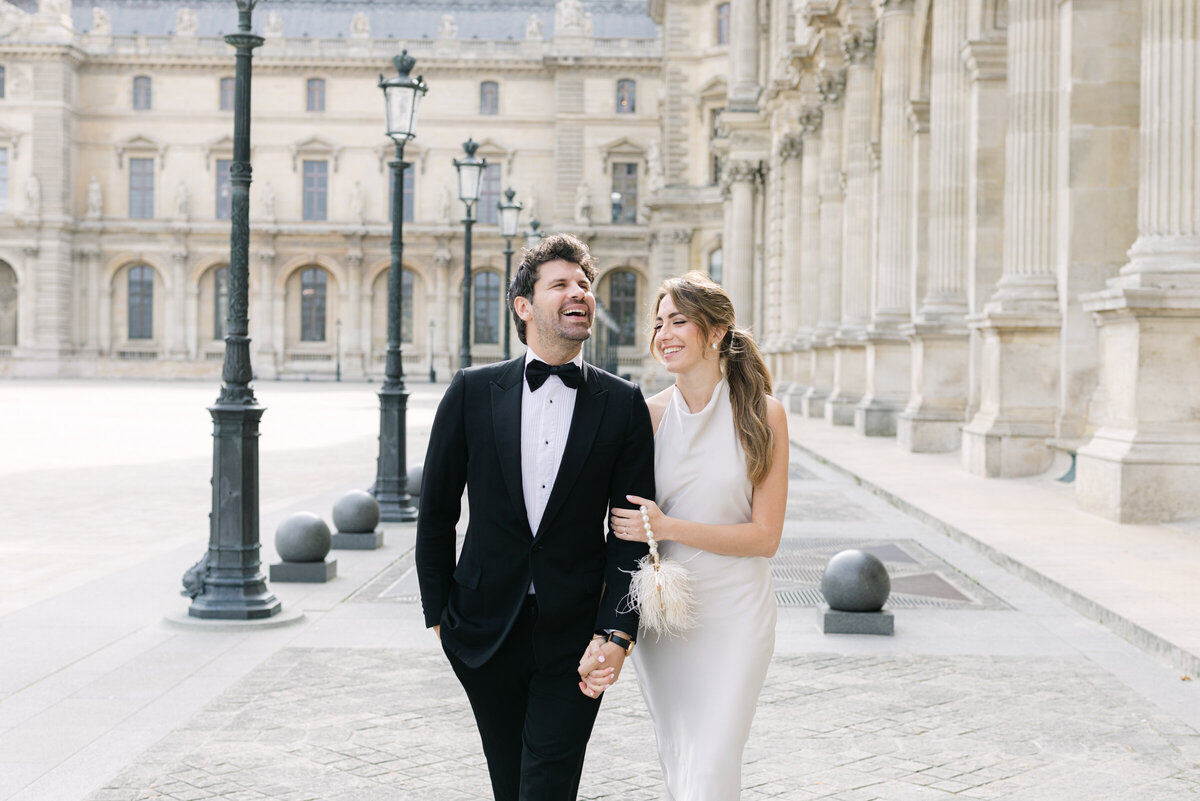 Engaged couple Anna and Nicolas candidly laughing and walking together near the Louvre in Paris