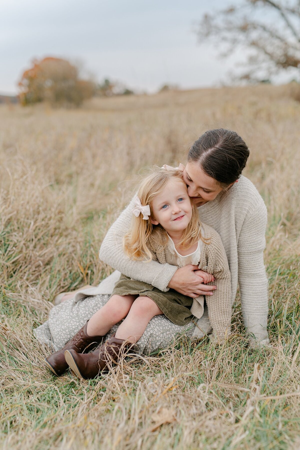 Little girl sits on her mom's lap while mom embraces her. Photo taken by family photographer, Abby Park Photography