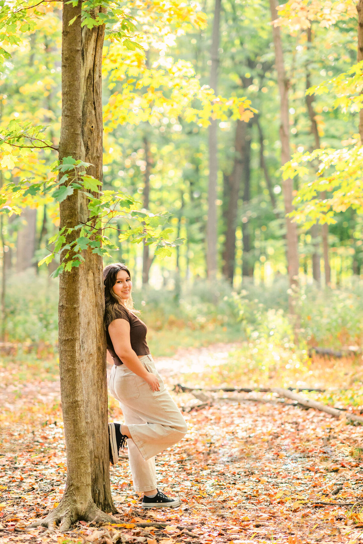 High school senior girl leaning against a tree