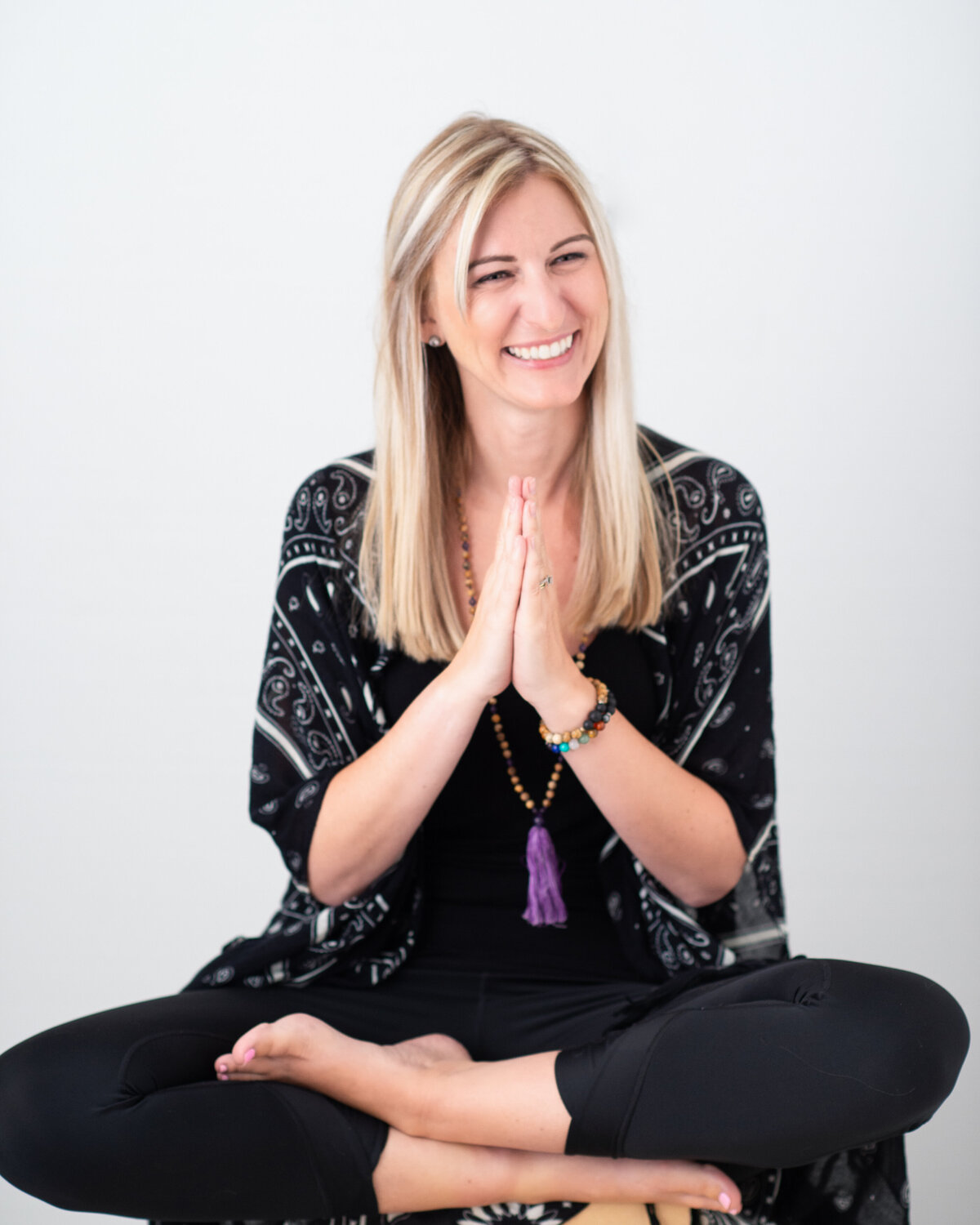 photo of yoga instructor sitting on floor cross-legged in namaste position.  Captured by Ottawa Branding Photographer JEMMAN Photography