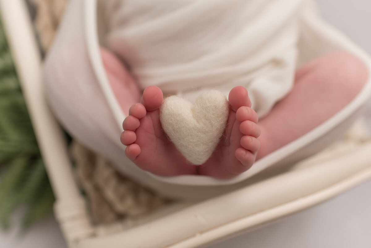 Picture of baby boy's feet holding a white felt heart
