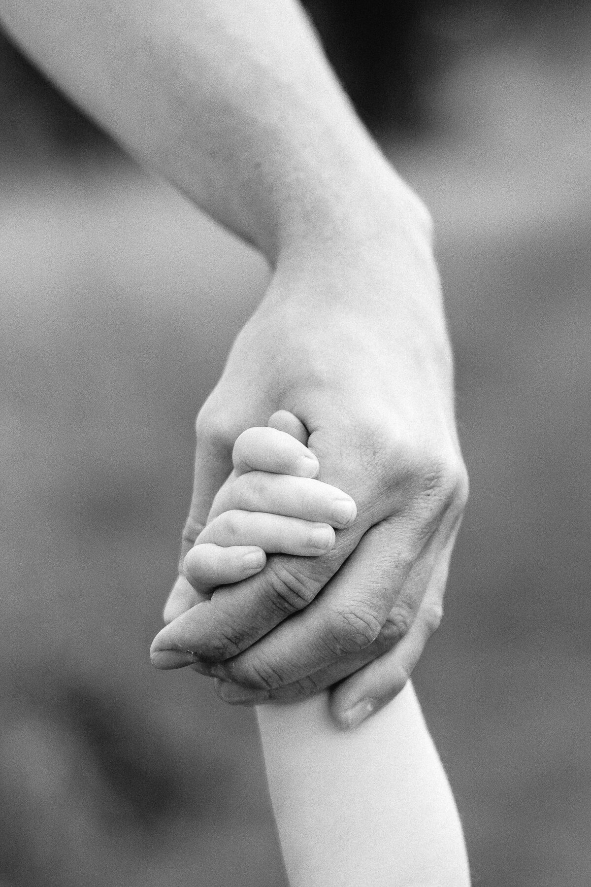 Artistic black and white photo of a parent holding their child's hand