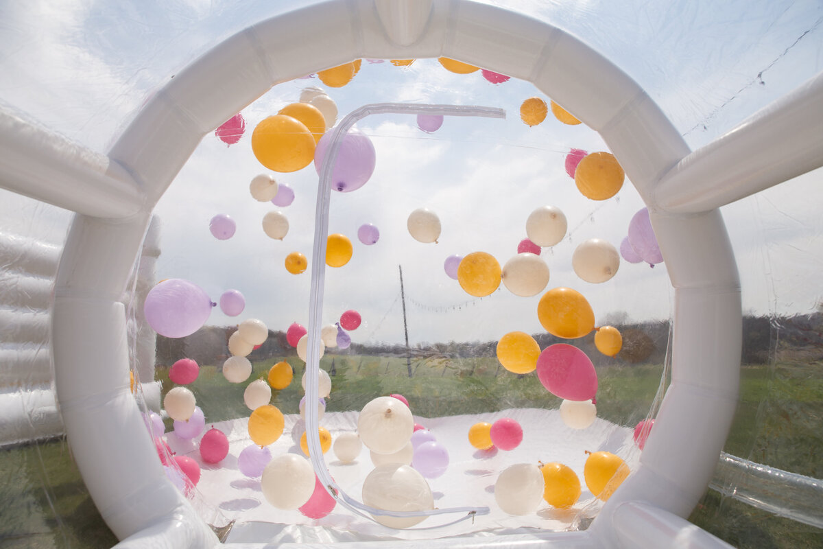 The view from inside a giant transparent bubble dome with colorful balloons flying around.