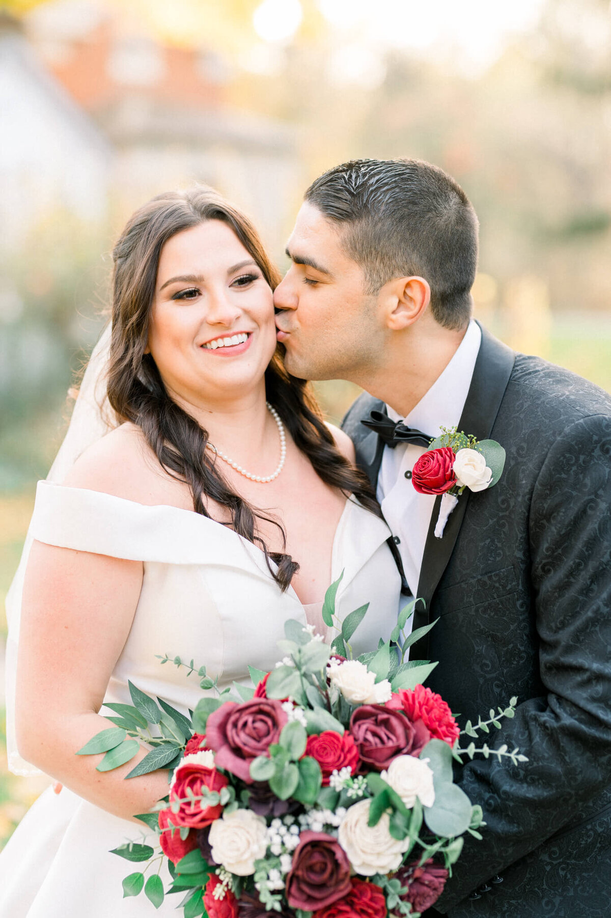 Groom leans in for a kiss to the bride on her cheek