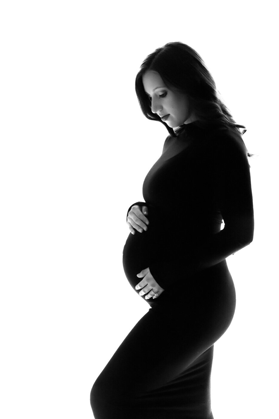 a portrait of a pregnant woman wearing a black long sleeve thight dress touching her belly