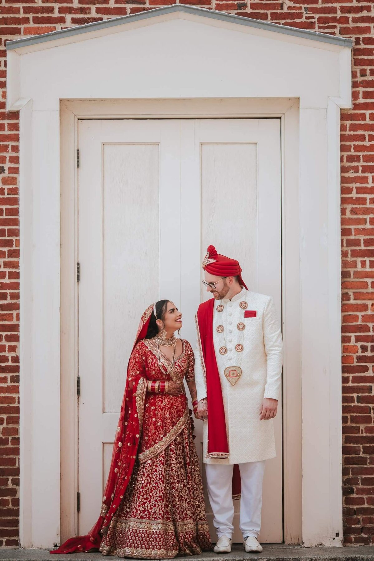 Indian fusion wedding couple during portraits. Holding hands hands standing side by side and enjoying some moments of tranquility before their barrat.