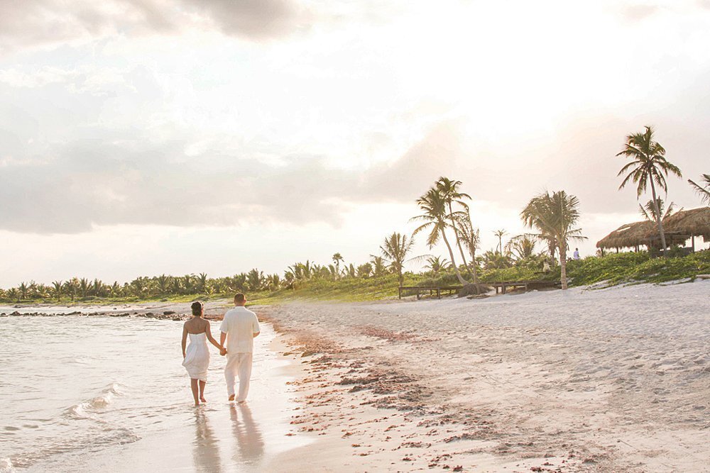 Newlyweds walking on palm tree beach in Tulum Mexico