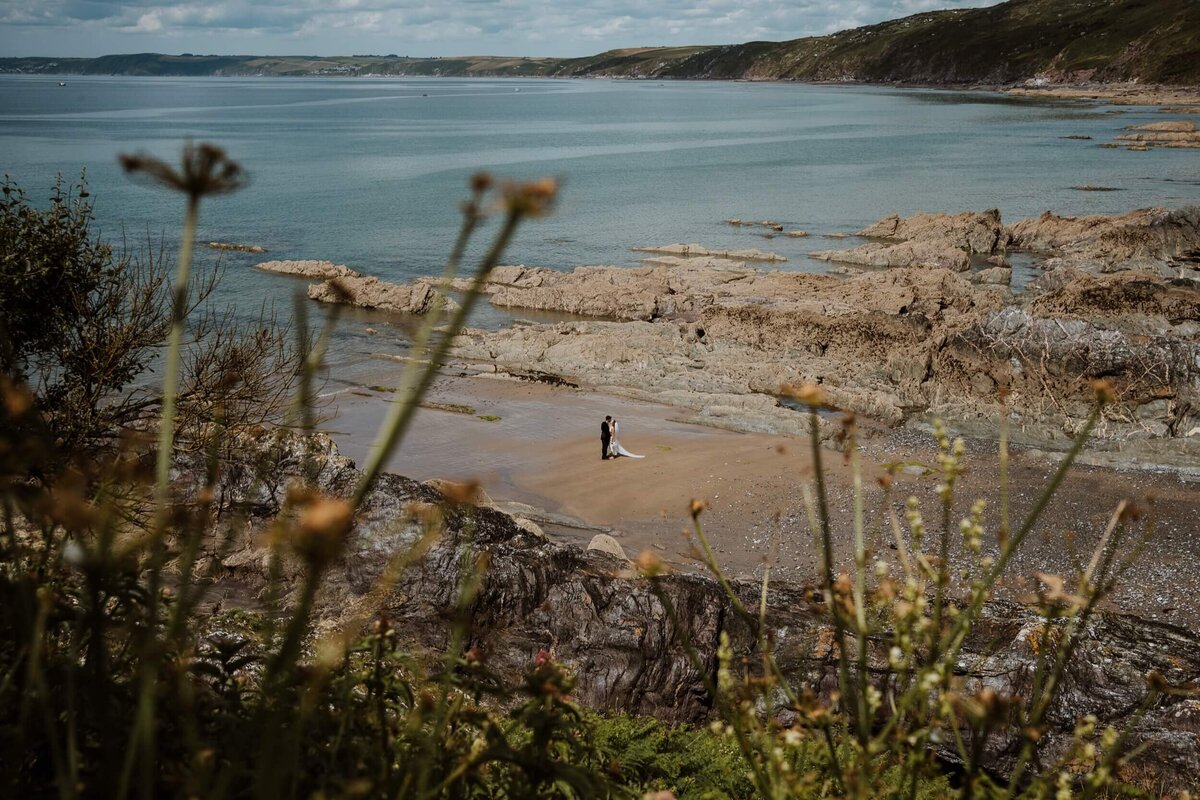 A view of the beach at Polhawn Fort with a couple standing int he sand