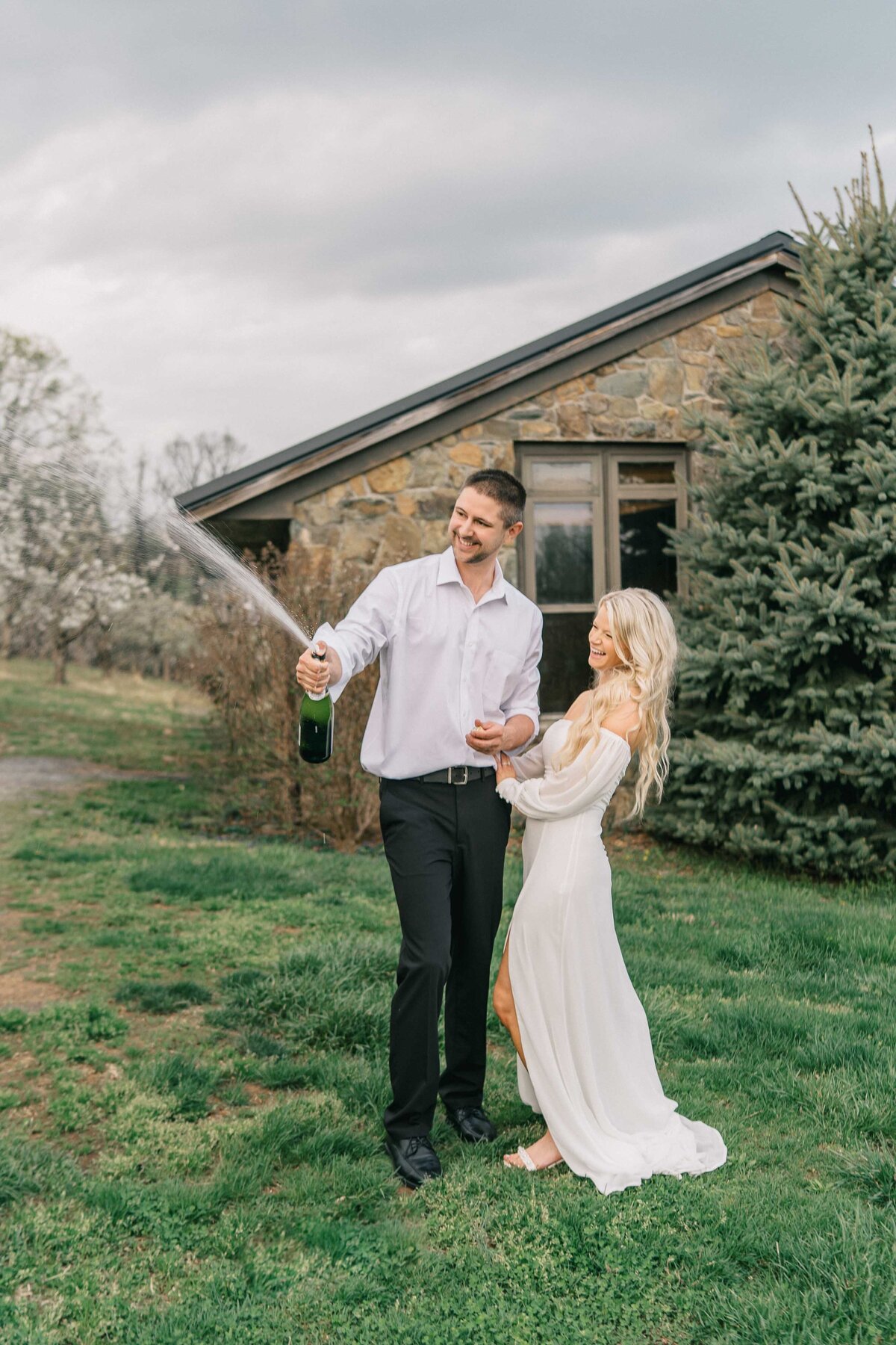groom and bride are excited opening a bottle of champaign to celebrate their wedding day