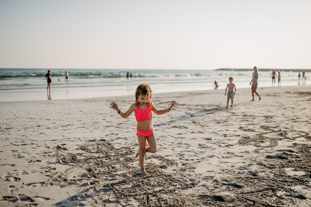 little-girl-jumping-in-the-sand-on-beach-during-su-2024-10-18-10-04-15-utc