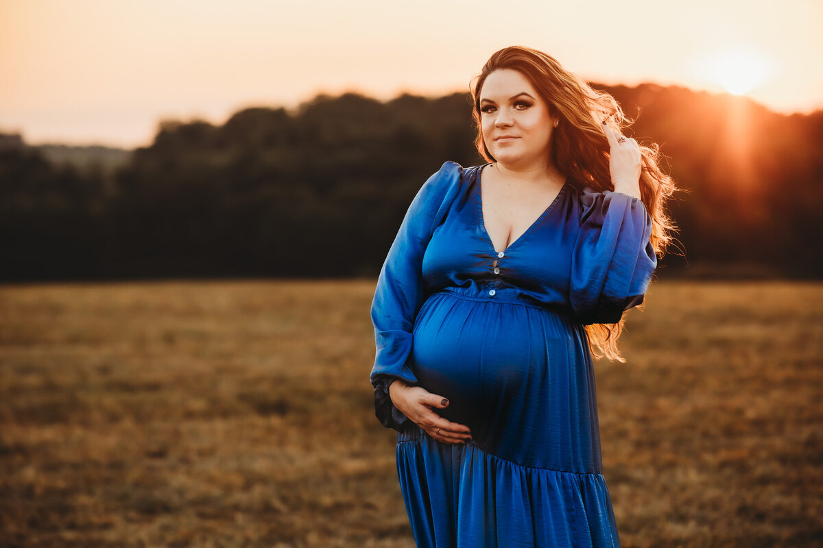 Pregnant women standing in golden glow of the sunset in a vibrant blue gown during her Harrisburg, PA golden hour maternity session