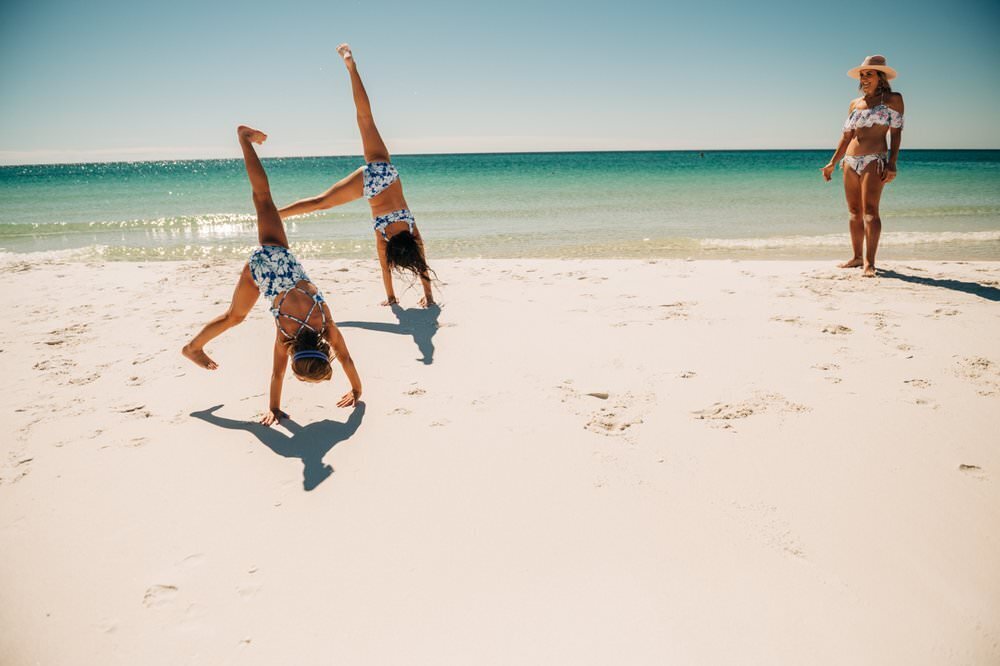 girl tumbling on Pensacola Beach with mom watching