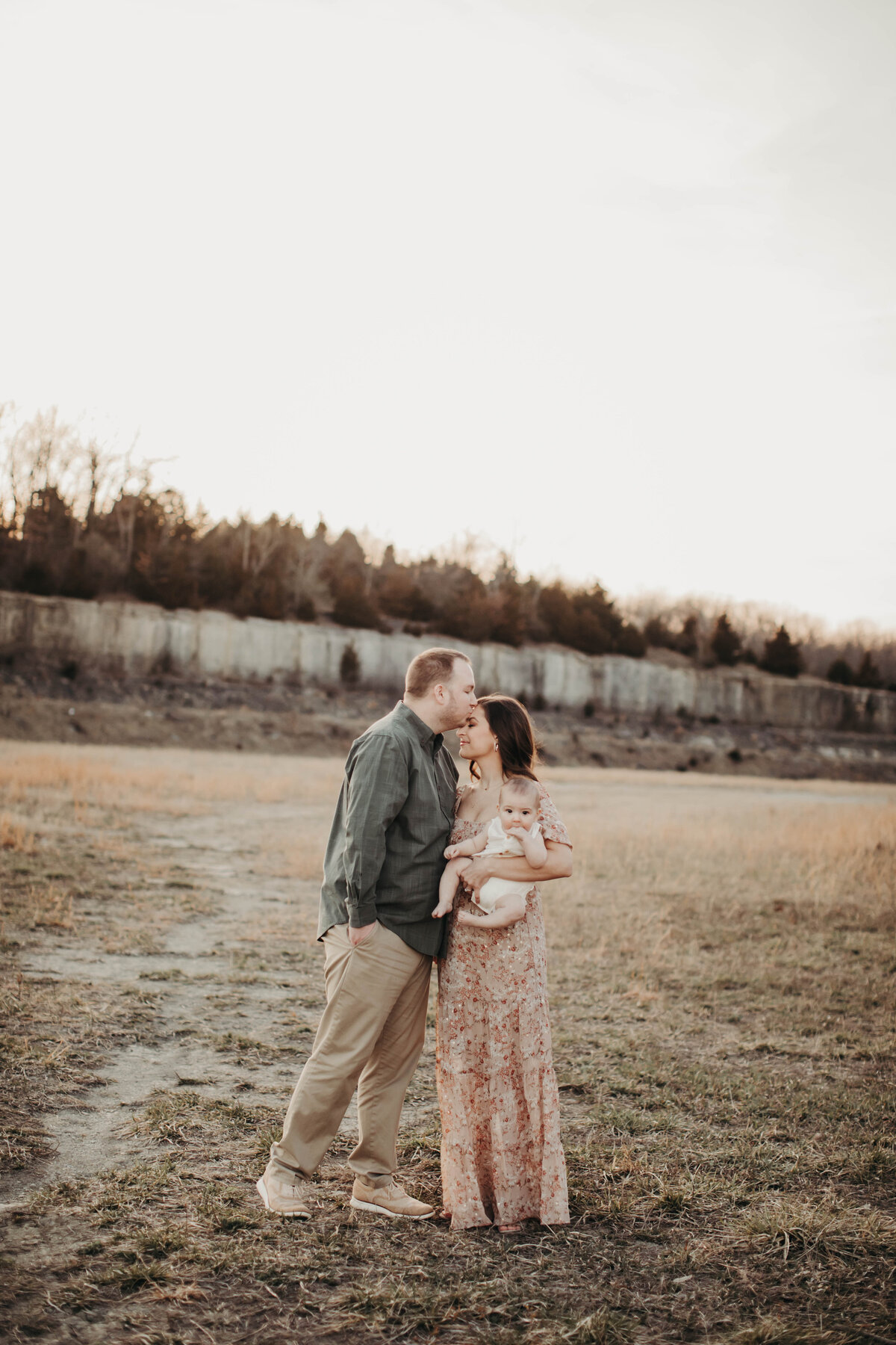 Golden hour portrait of parents cradling their baby boy, all bathed in warm light.