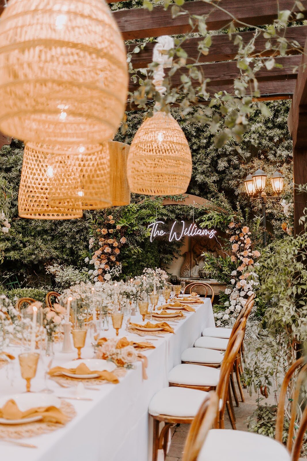 Rattan lanterns hanging over a rectangular table with gold napkins and goblets at Franciscan Gardens