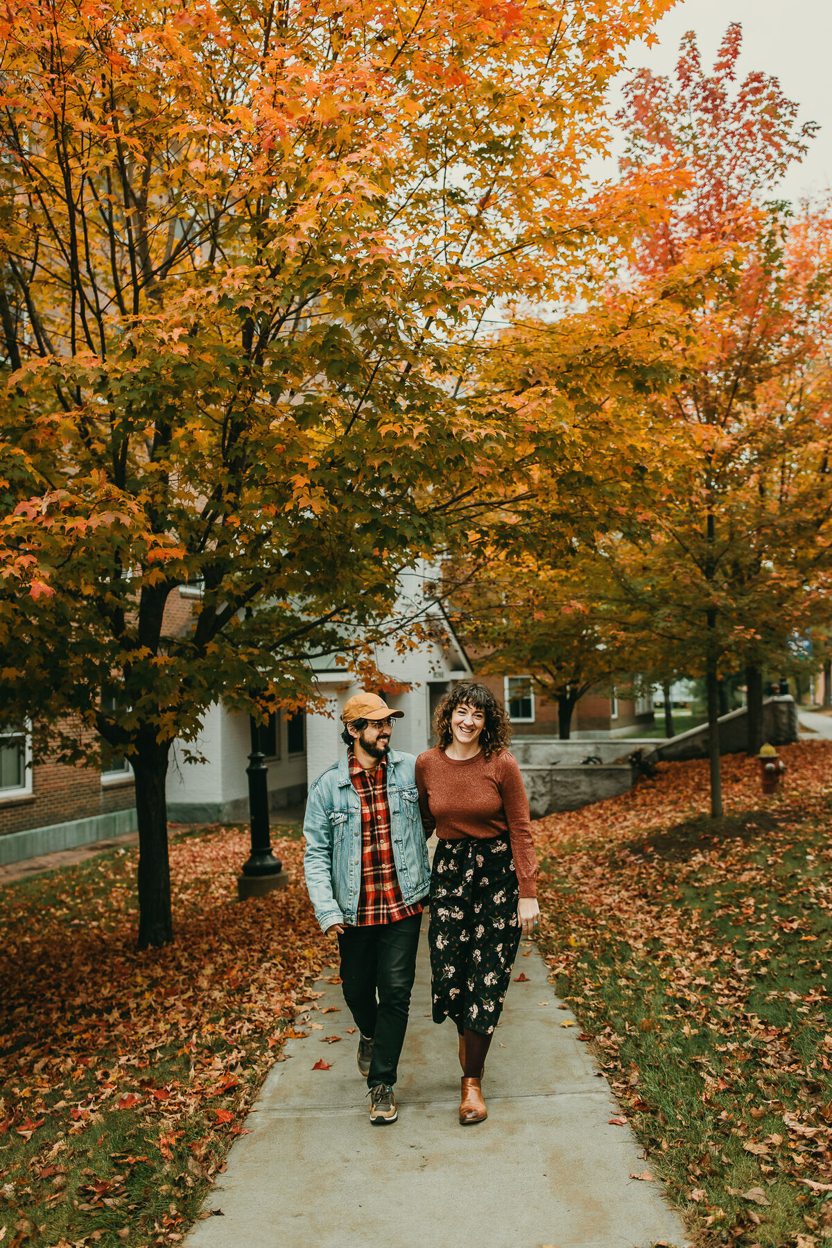 Couple walks together on tree lined pathway with Fall folaige