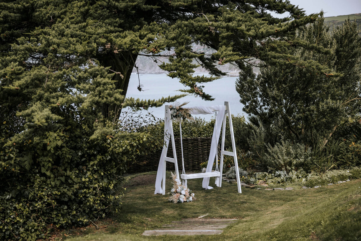 A white bench sitting on a lawn under a tree