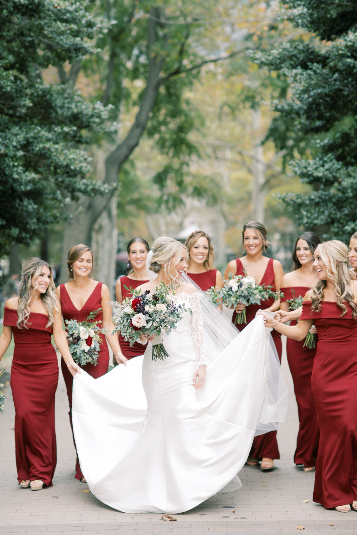 bridesmaids holding bride's gown during outdoor bridal portraits