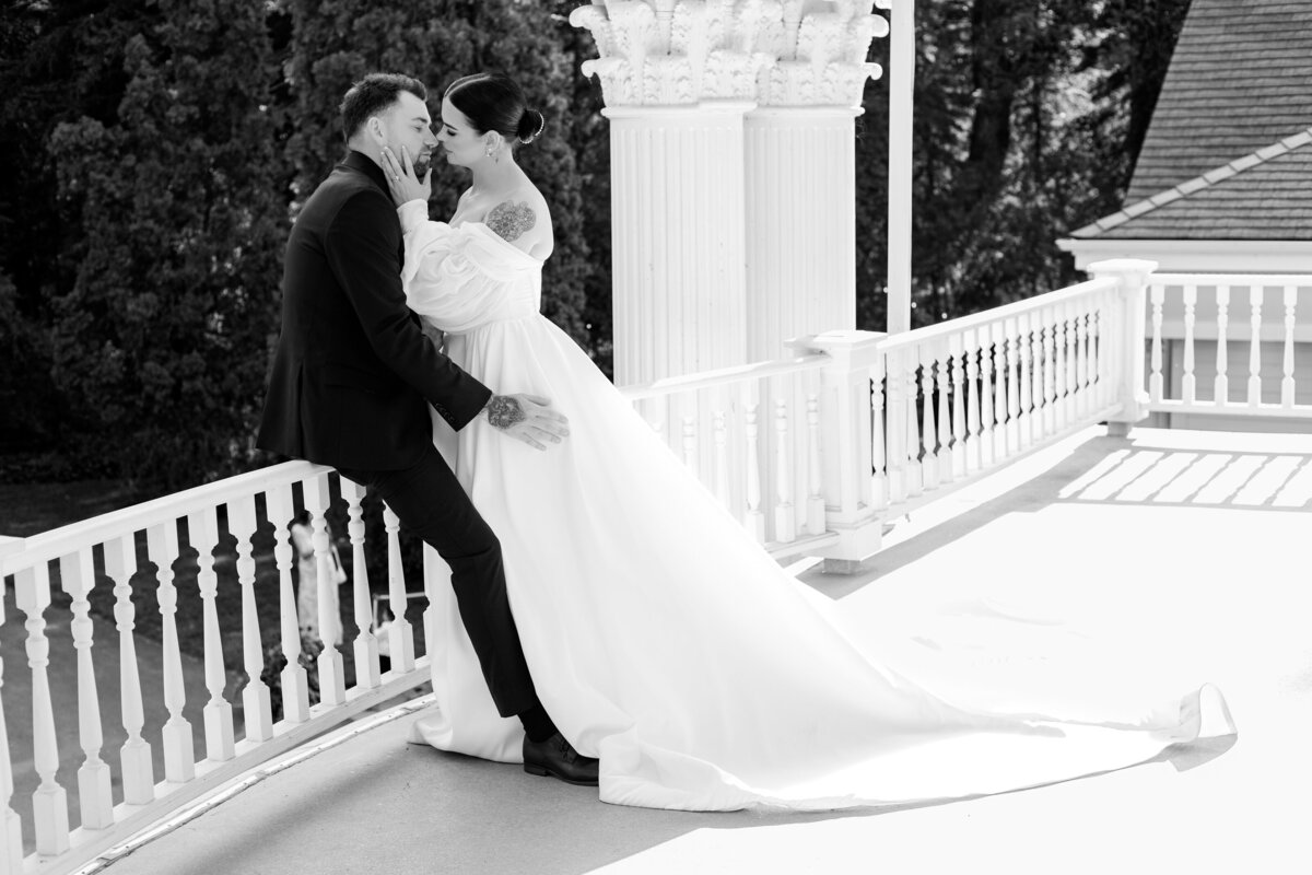 Bride leans into groom on the balcony of the Norland Estate in Lethbridge