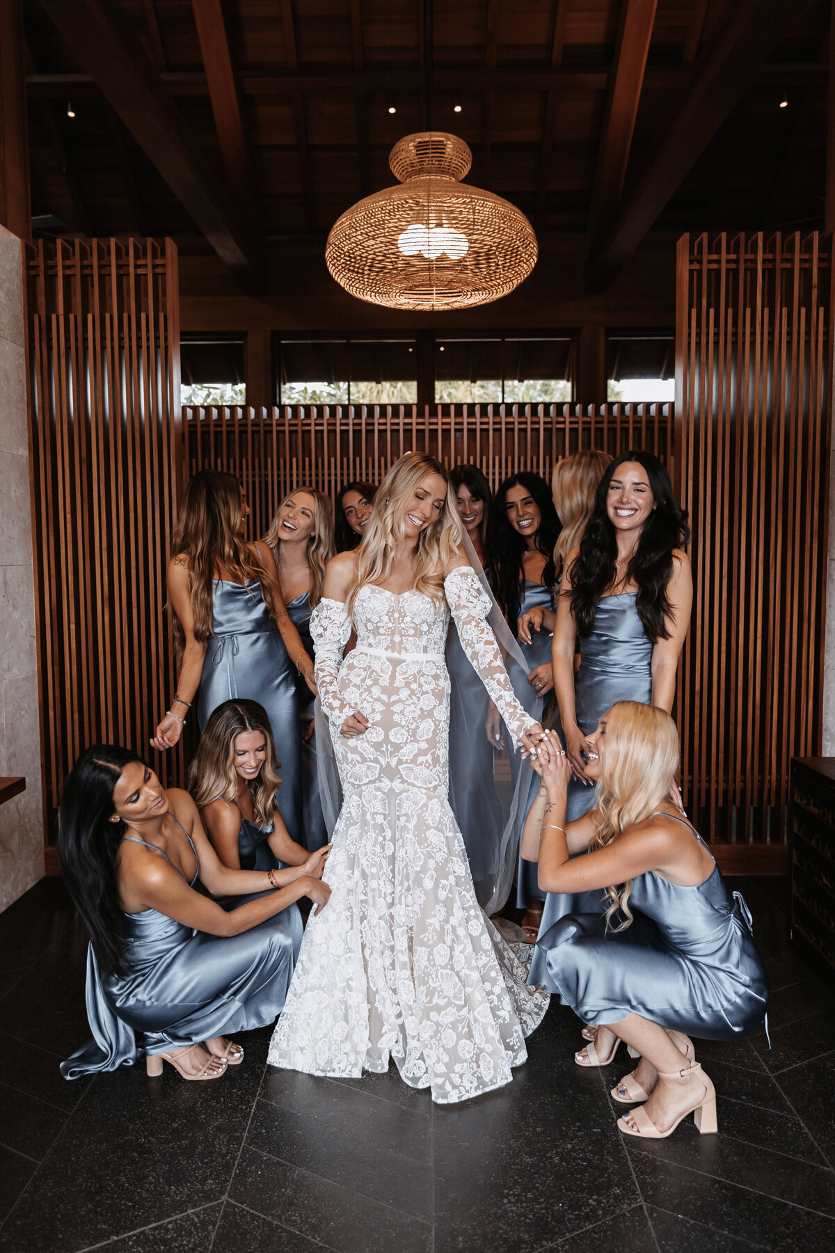 Wedding photography,  bride surrounded with bridesmaids wearing satin blue dresses
