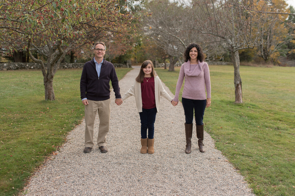 Family of three holding hands across a path