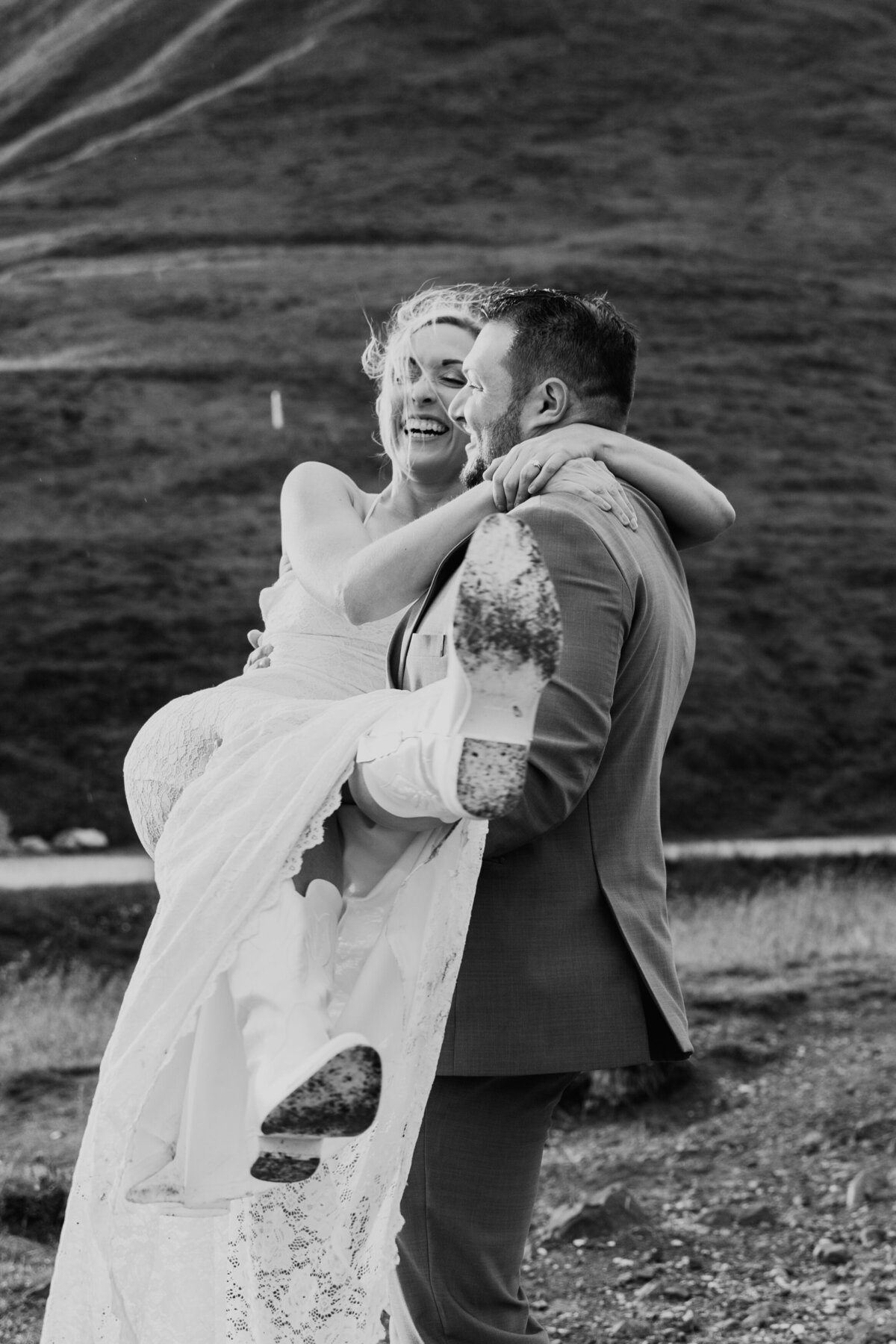 Black and white photo of groom lifting bride during mountain elopement