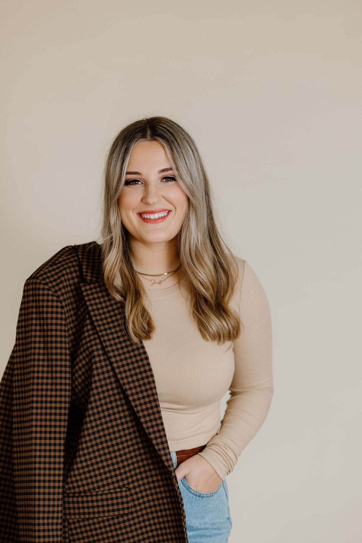 candid headshot portrait of graduate student in tan top, jeans, and brown sports coat