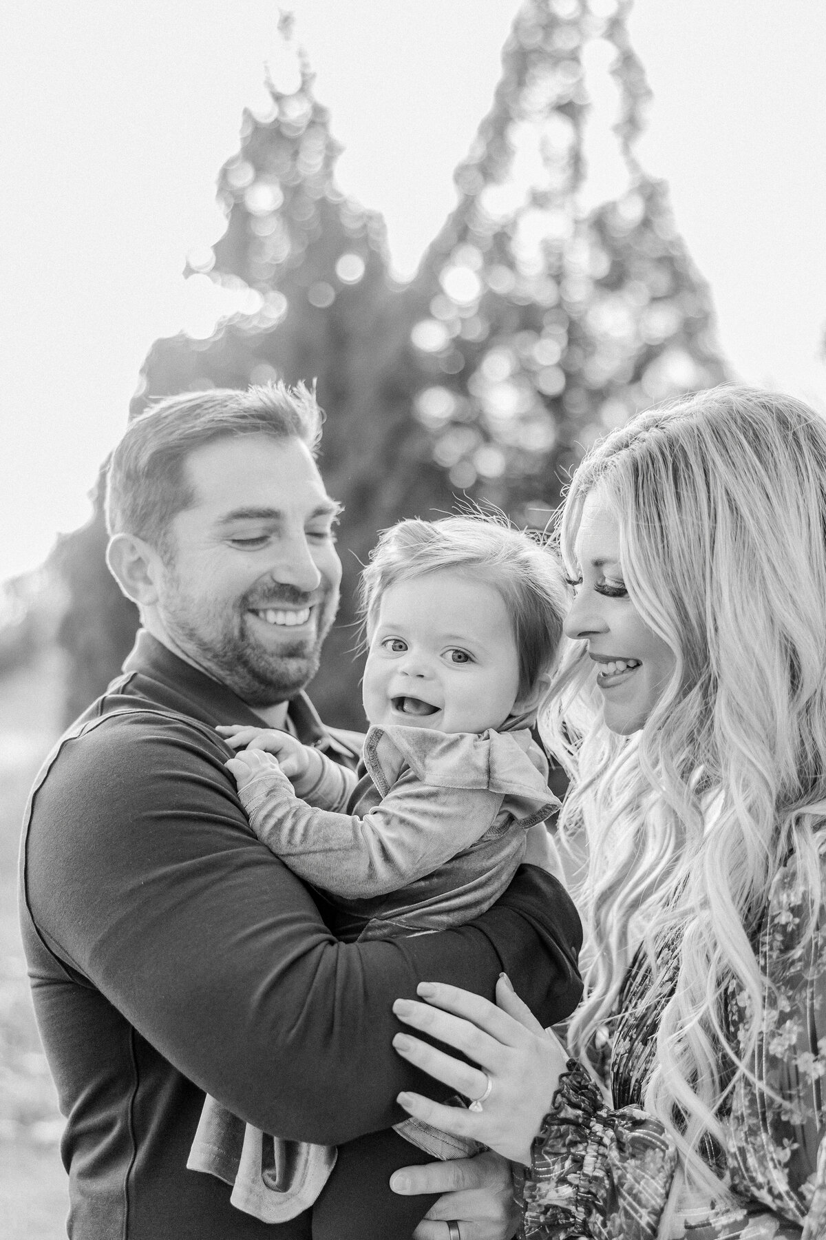 black and white photo of baby snuggled with mom and dad