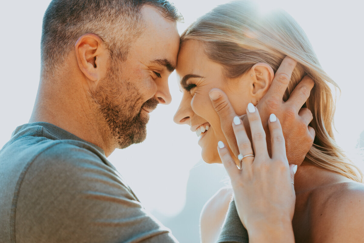 man holds womans face with sunlight behind them