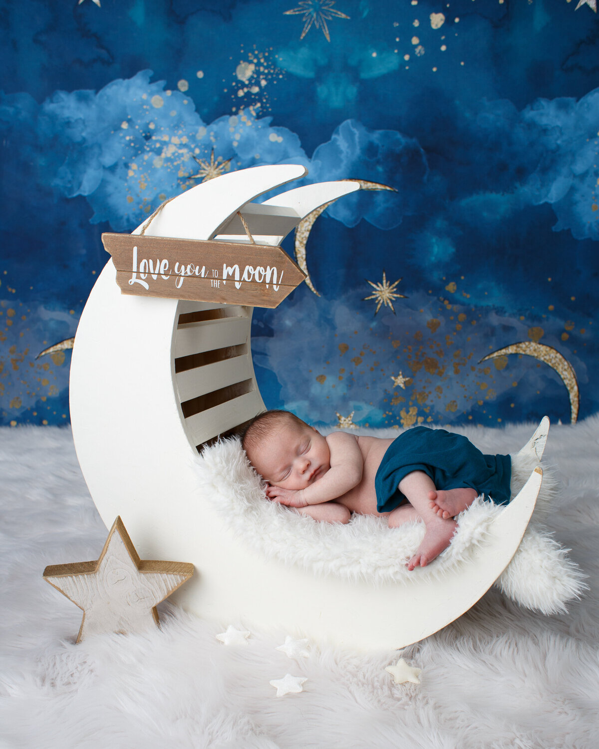 Portrait of a newborn baby sleeping on a moom photo prop against a starry night sky background