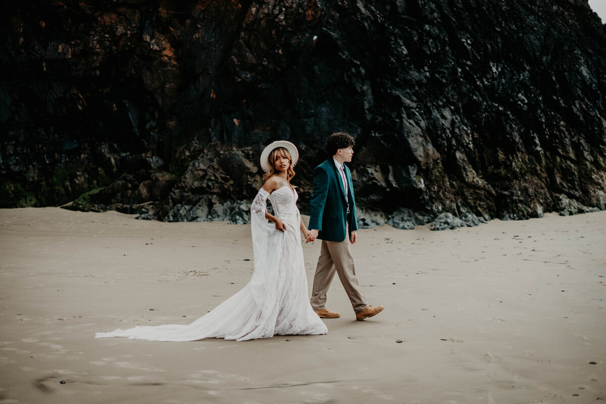 Couple walking across the beach after Oregon Coast elopement