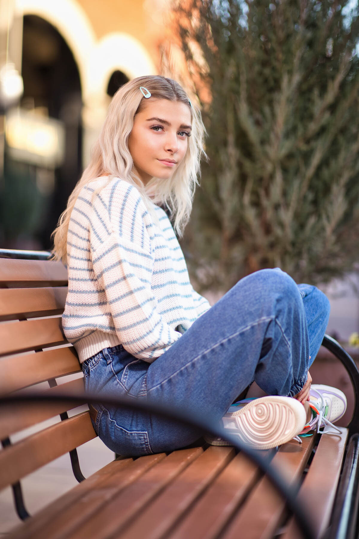 Senior girl posing on bench for senior photos at Trolley Square in Utah.