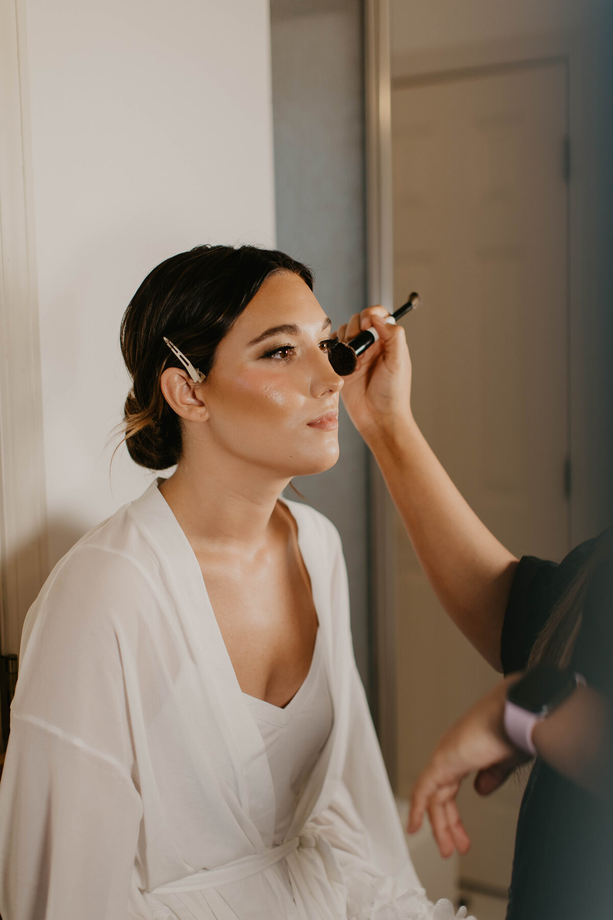 Bride putting on blush before wedding. 