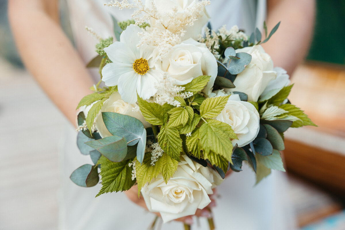 Close-up of white rose bridal bouquet with greenery