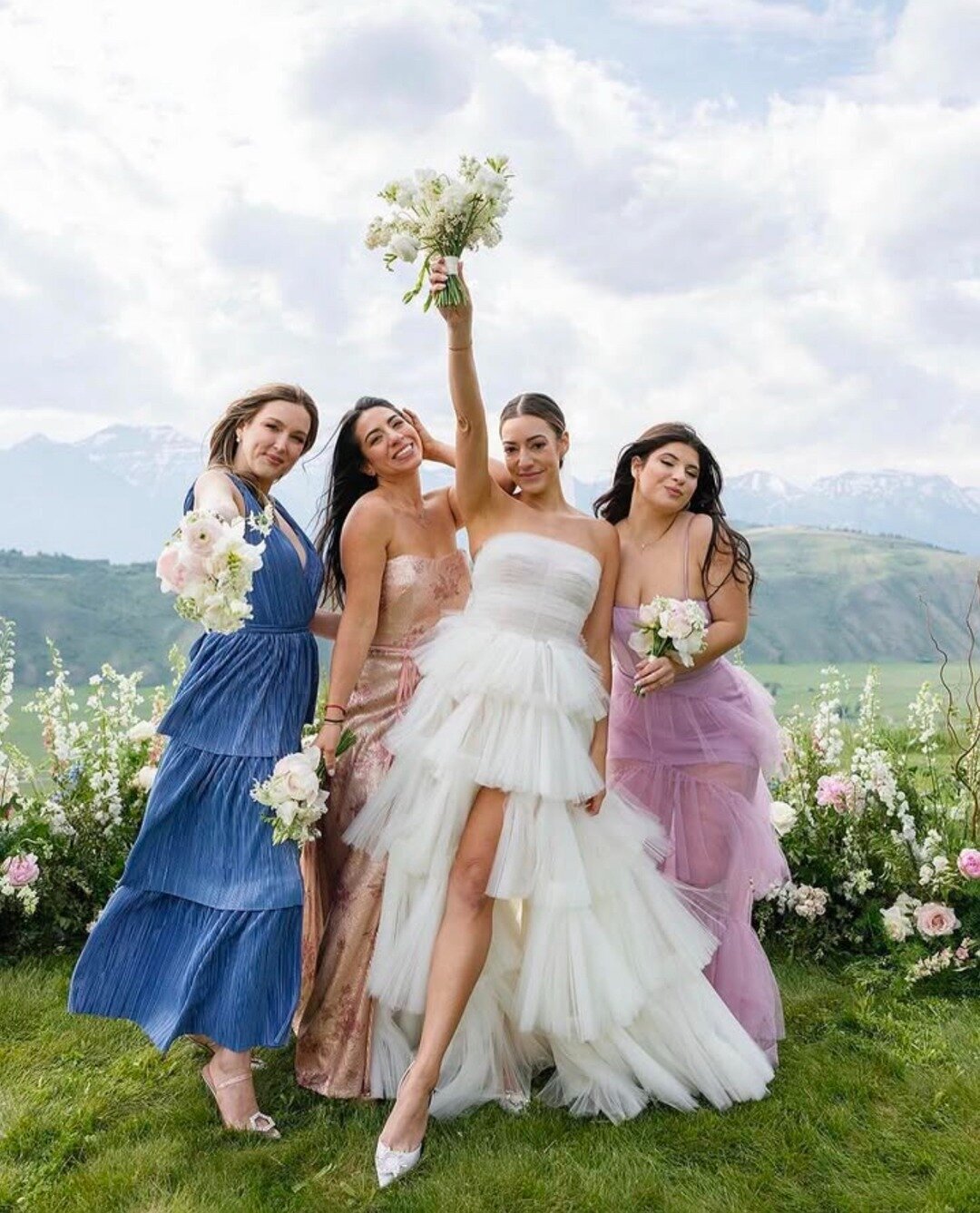 Bride poses with her squad in front of a luxury floral ground install and the sweeping view of the Tetons from Teton Valley