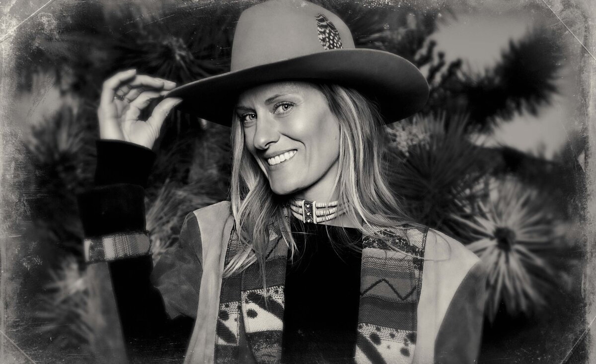 Country music photo Amanda Olsen black and white holding tan cowboy hat brim large Joshua tree behind