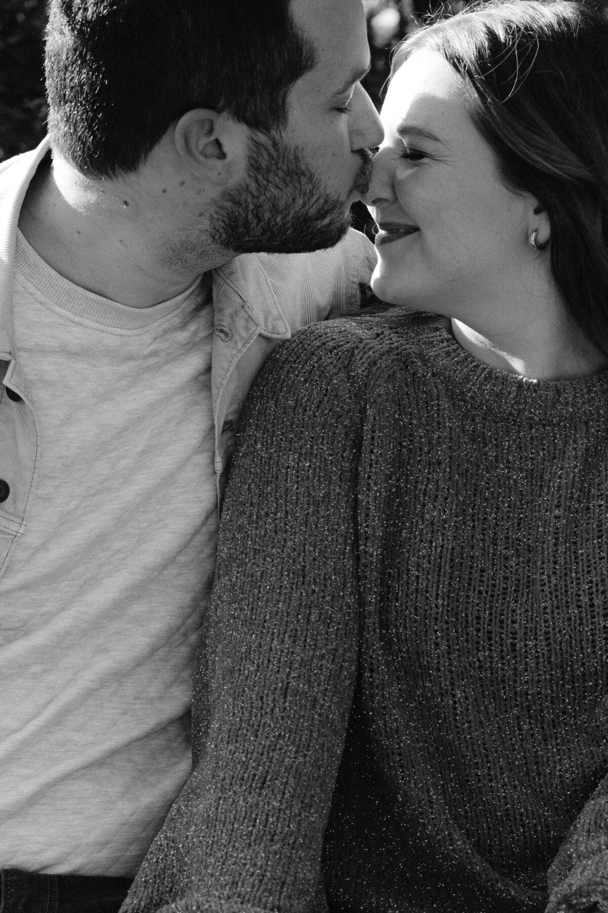 black and white photo of man kissing womans nose while woman is smiling