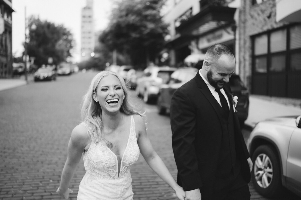 Bride and groom walking hand in hand down the street laughing, taken by Asheville Wedding Photographer Simon Anthony Photography