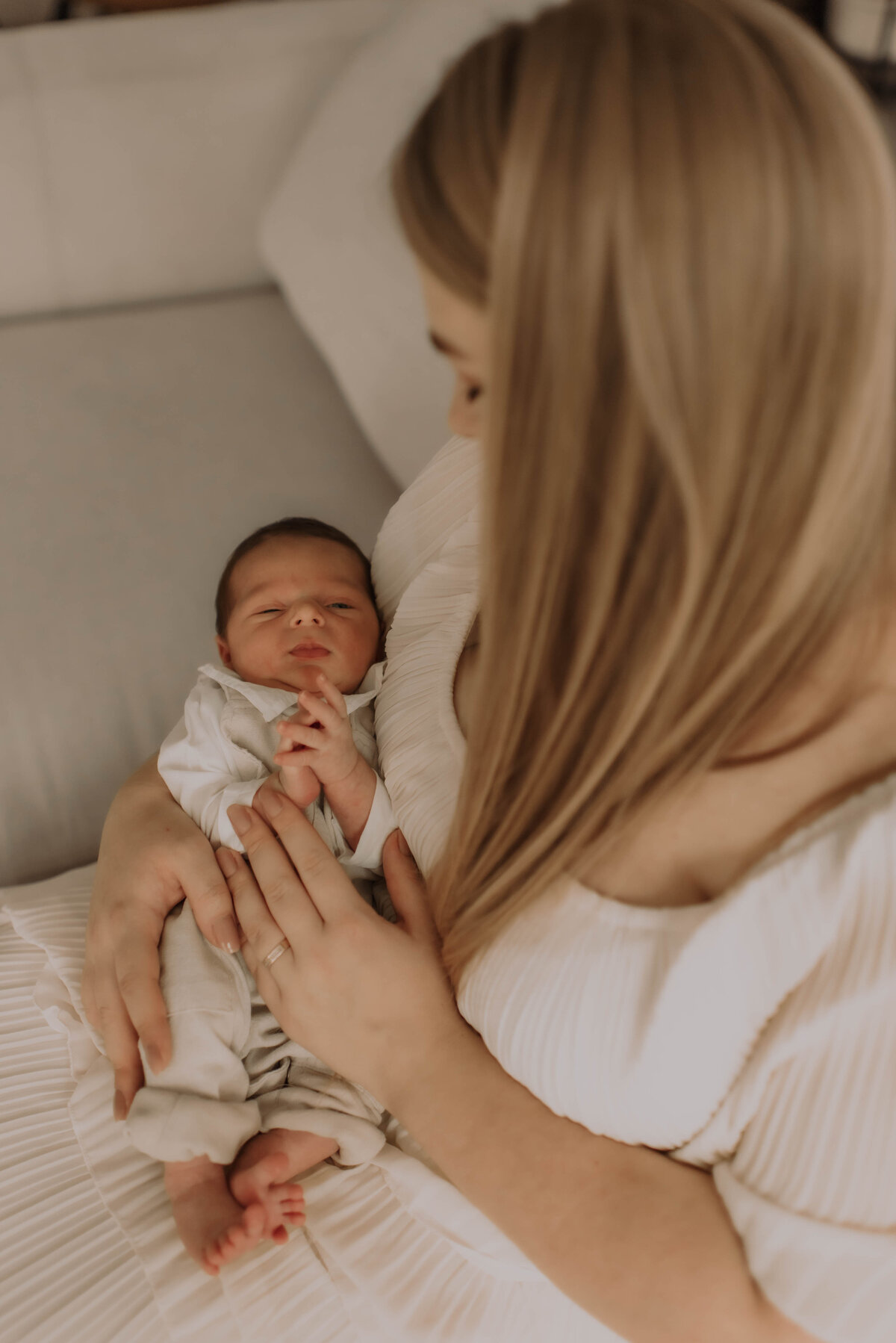 Mama kijkt pasgeboren baby liefdevol aan tijdens newbornshoot