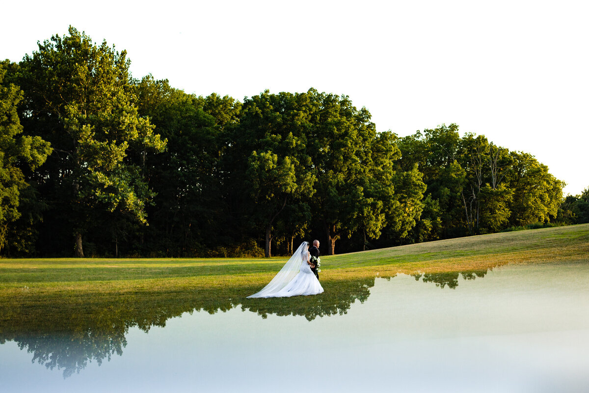 One of the top wedding photos of 2020. Taken by Adore Wedding Photography- Toledo, Ohio Wedding Photographers. This photo is of a bride and groom walking together in a field of grass at Nazareth Hall in Toledo Ohio