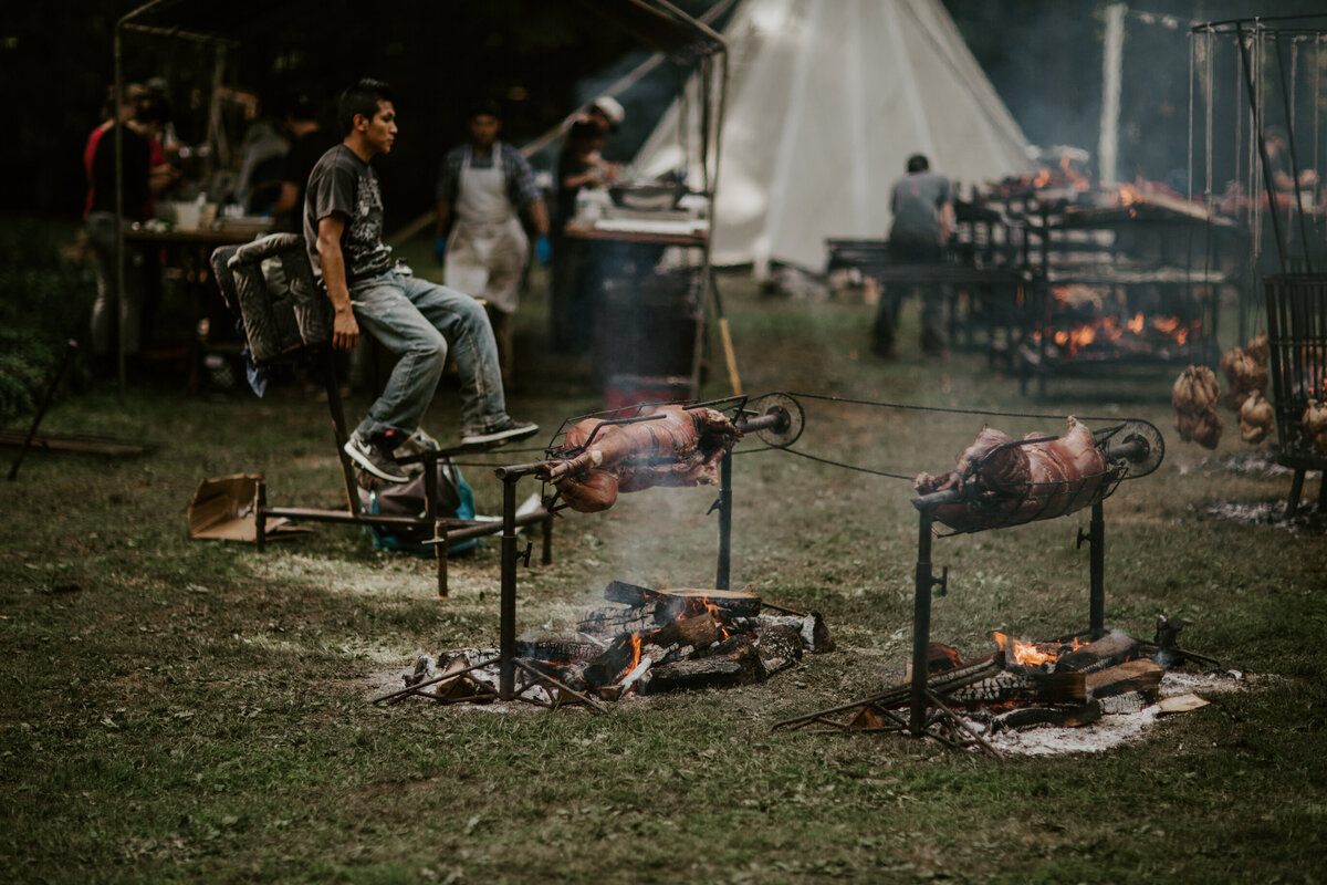 Pit-fire roasting at outdoor glamping wedding