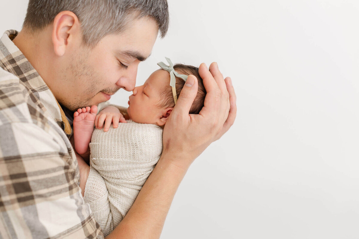 Dad in light colored neutrals holding newborn baby up to his nose, so their noses are touching. Sweet newborn photos in Ashlie Behm Photography's portland, oregon portrait studio