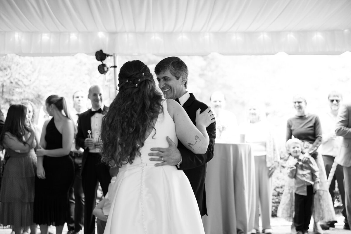 Two people dancing at a wedding reception with guests watching on.
