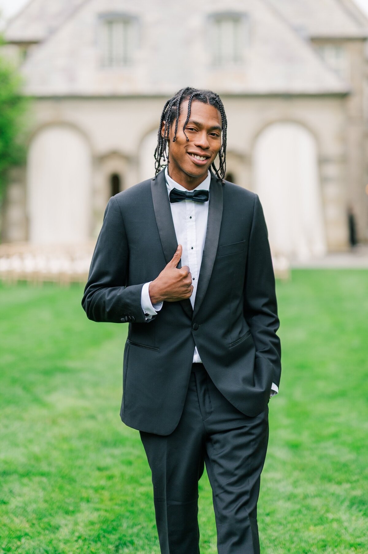 A groom smiling and walking outside of Glen Manor House. 