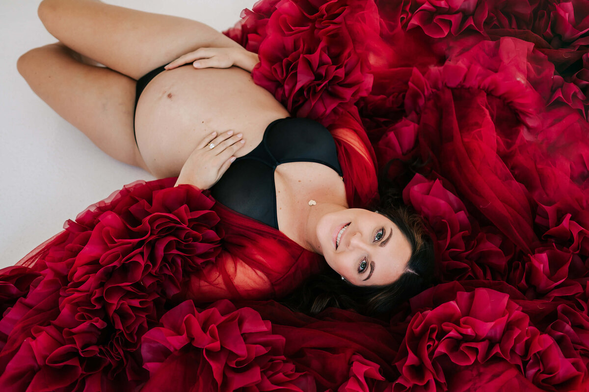 pregnant mom smiling laying on ground in maternity photography studio in Branson