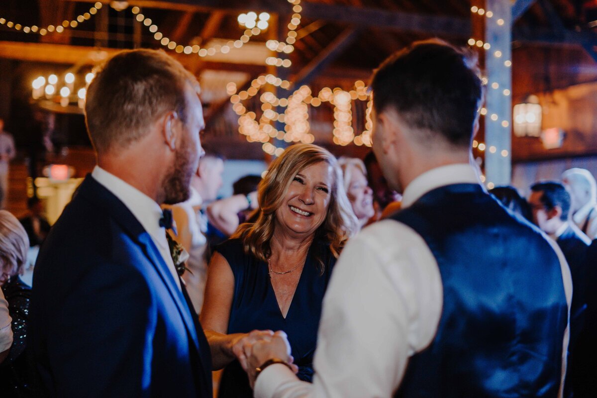 a mother encouraging groom to come and dance at reception