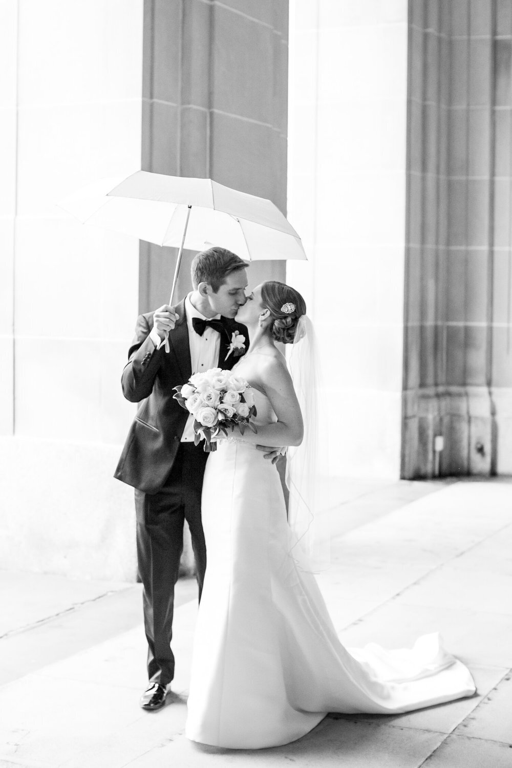 bride and groom kiss under an umbrella on a rainy day in Chicago