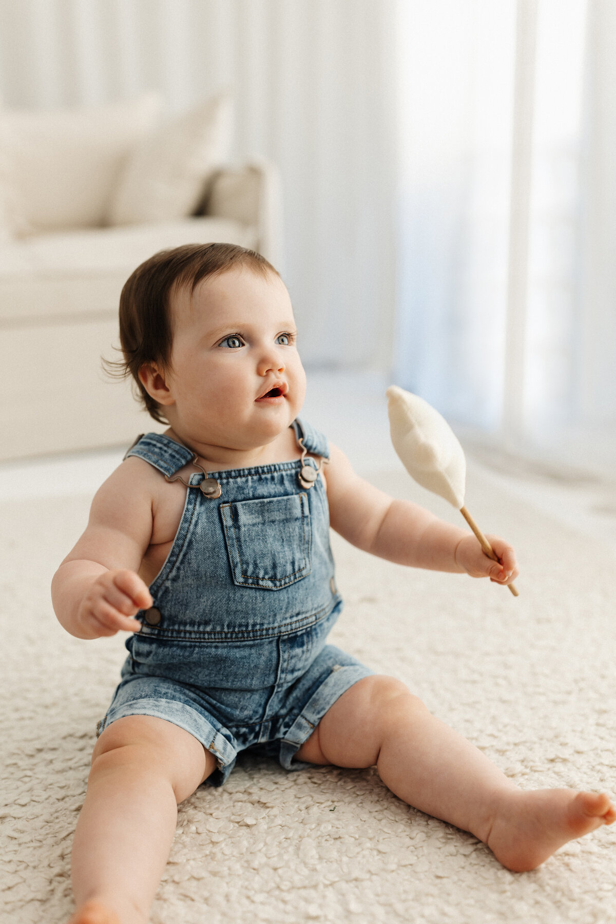 A little boy holding a star wearing a cute denim overalls and sitting on the floor in the photography studio in christchurch