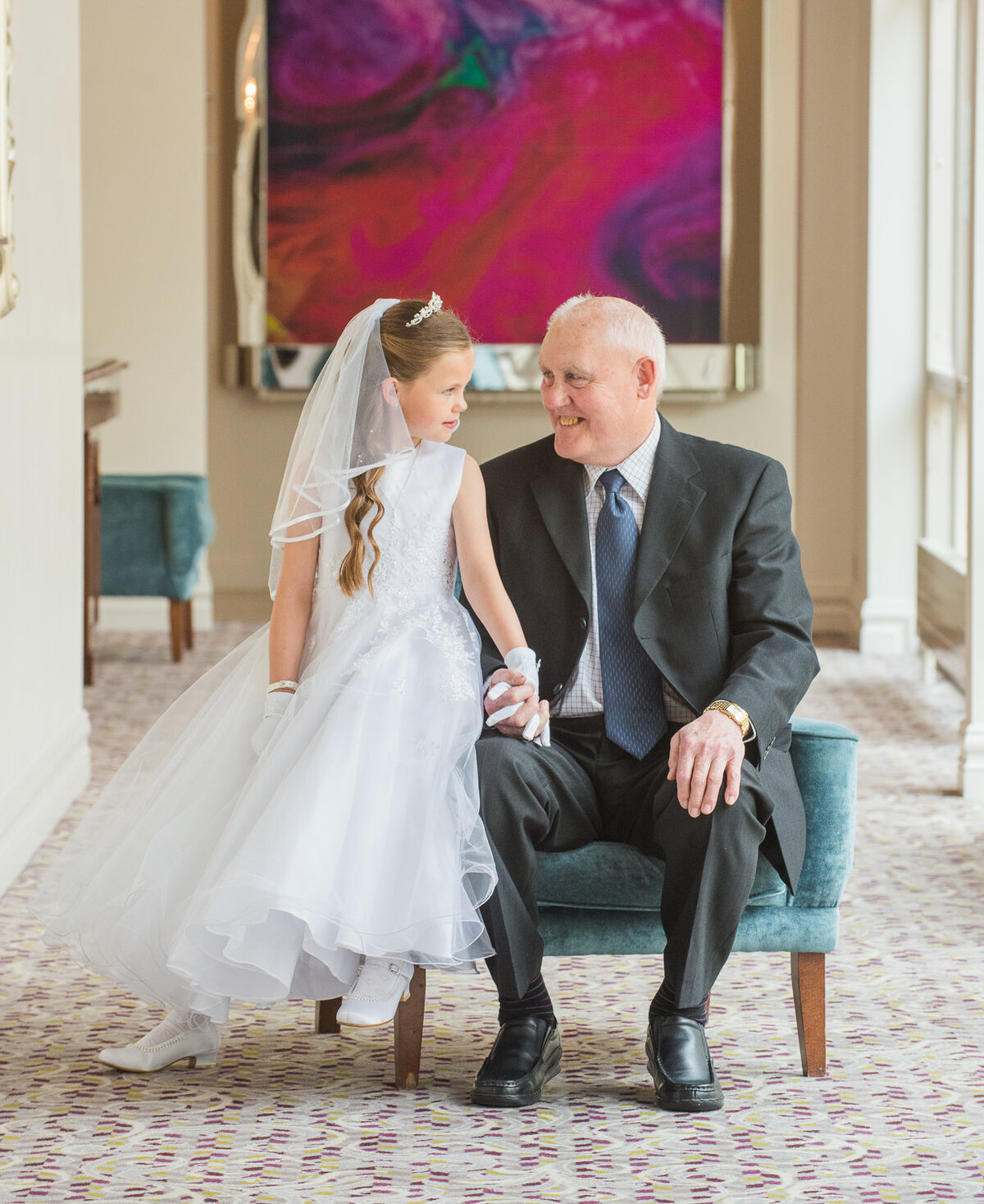 communion portrait of a grand daughter sitting  with her grandfather, looking at each other smiling